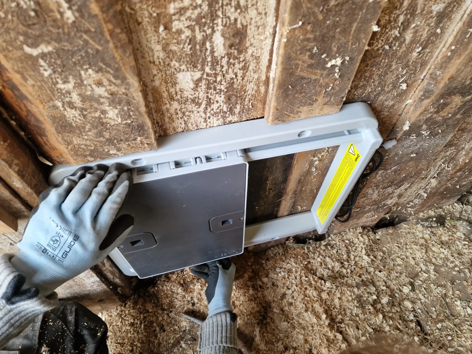 Gloved hand holding the door frame against the new opening to check the fit.