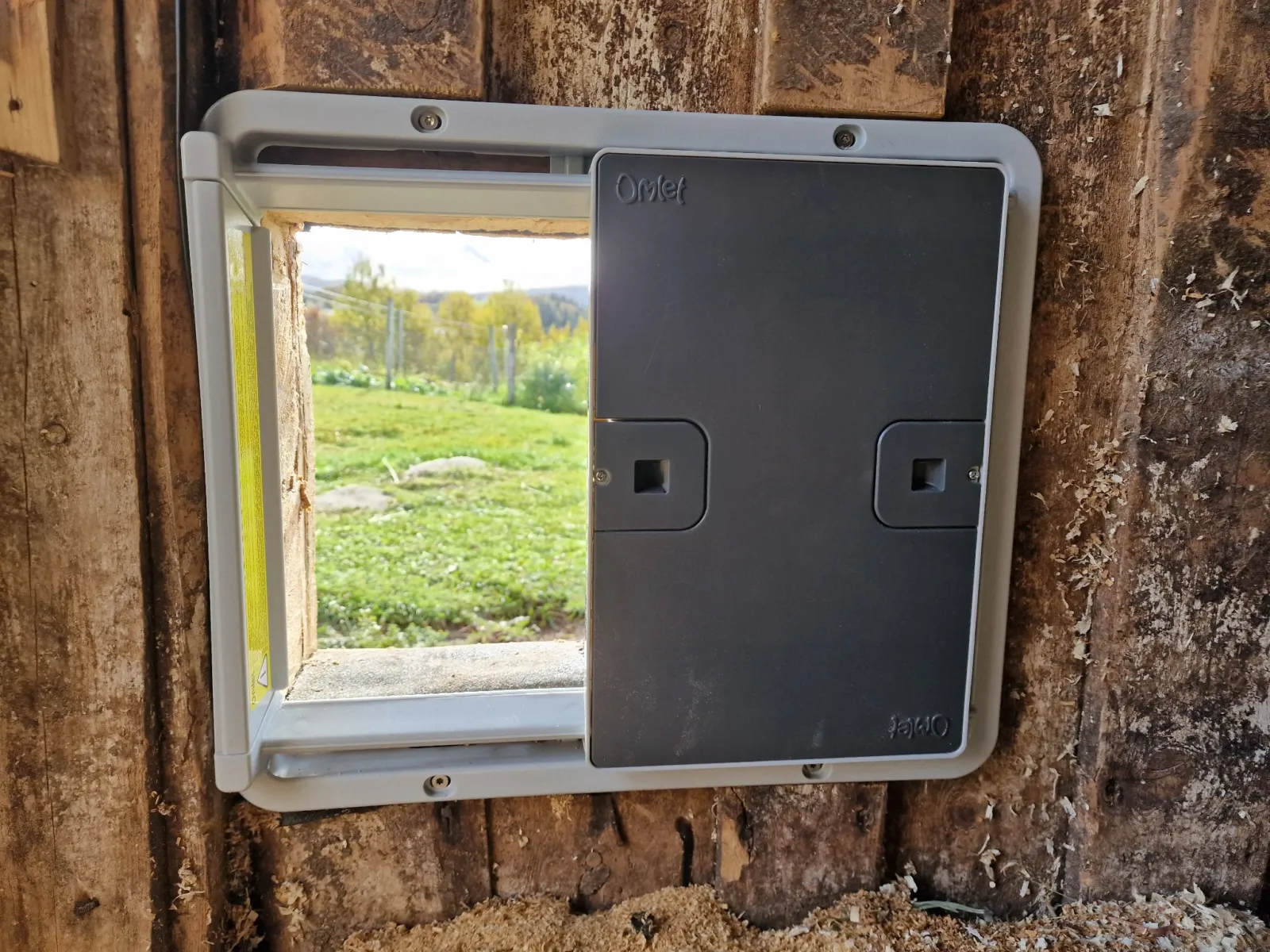 Grey Omlet Smart Autodoor fitted to the inside of the barn wall, with the door half open.
